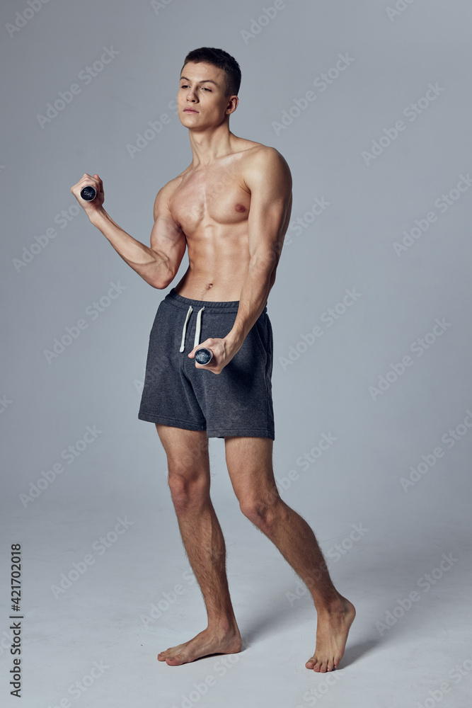Fototapeta premium sports man in shorts dumbbells in hands training gym 