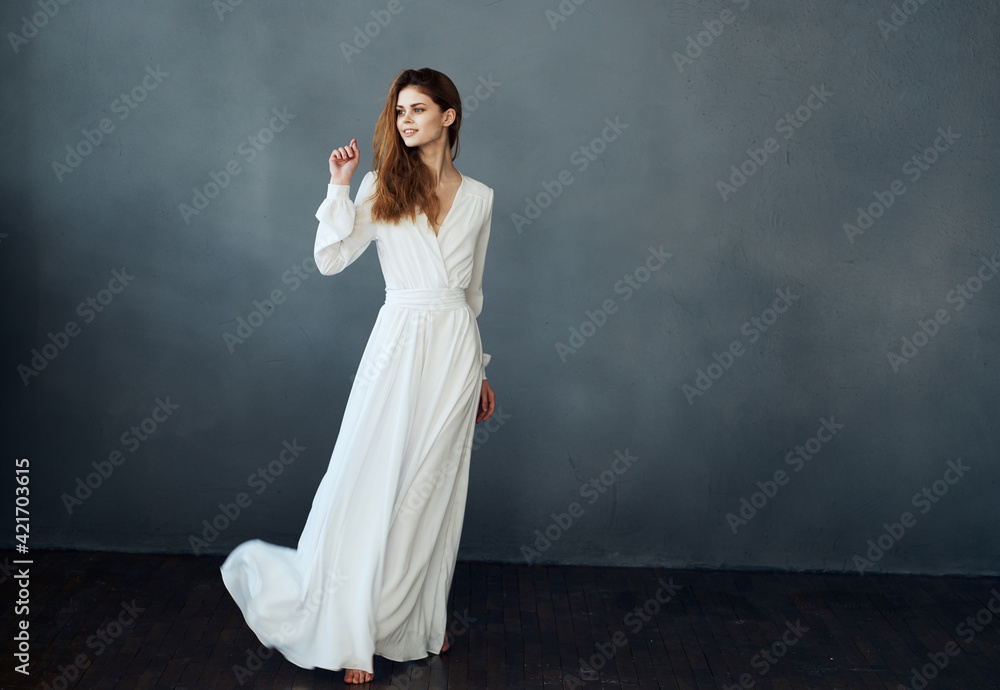 Woman on a gray background in a white dress dance model in full growth Woman on a gray background in a white dress dance model in full growth