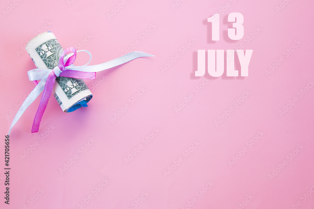 calendar date on pink background with rolled up dollar bills pinned by pink and blue ribbon with copy space. July 13 is the thirteenth day of the month