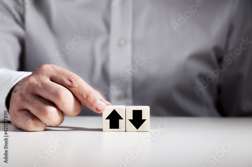 Slika na platnu Businessman makes a choice between the up and down arrow icons on wooden cubes