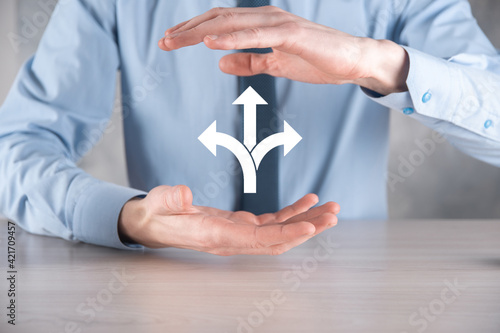 Businessman in a suit holds a sign showing three directions. in doubt, having to choose between three different choices indicated by arrows pointing in opposite direction concept. three ways to choose photo