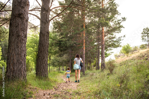 a mother walking with her son through the forest © OMP.stock
