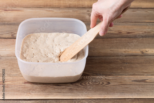 Rye sourdough on flour sourdough in a container on a wooden table. Fermentation.