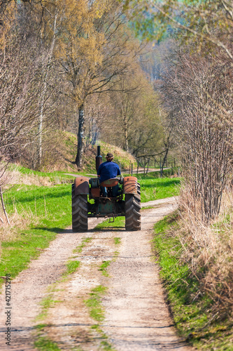 Old tractor driving on a dirt road in the spring