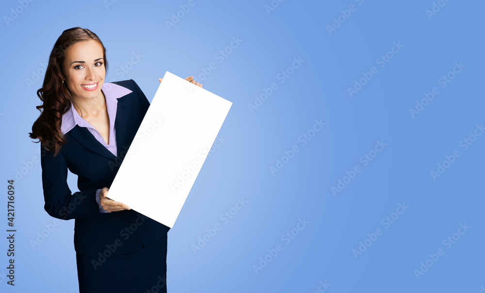 Happy smiling woman in black confident suit showing blank white signboard. Business and advertising concept. Copy space empty place for some text. Blue color background.. Happy smiling woman in black confident suit showing blank white signboard. Business and advertising concept. Copy space empty place for some text. Blue color background..