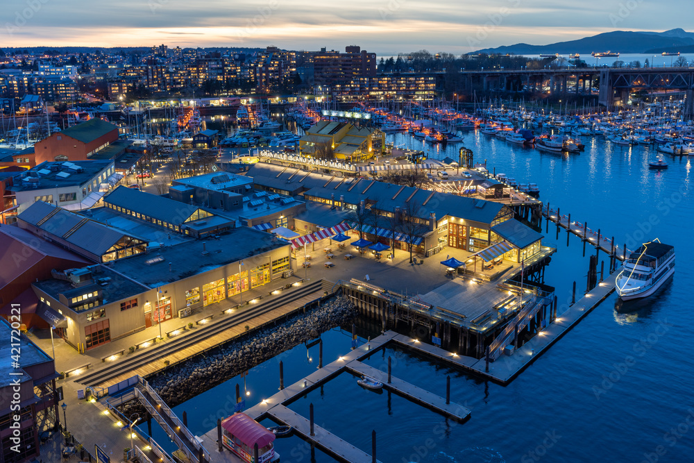 Granville Island Public Market, Marina and Fishermen's Wharf Float in dusk. Vancouver city buildings skyline in the background. Vancouver, Canada.