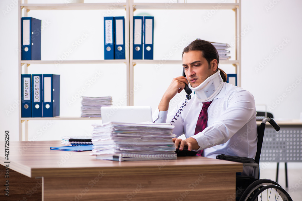 Neck injured young male employee in wheel-chair at workplace Neck injured young male employee in wheel-chair at workplace
