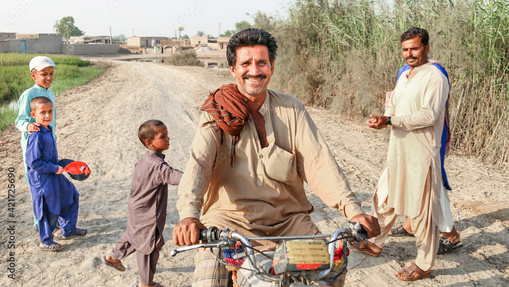 a farmer is riding a bike and feeling happy in a village - obrazy, fototapety, plakaty 