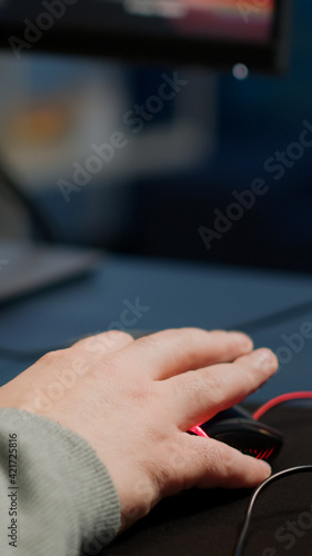 Close-up of man hands gamer playing video game using RGB keyboard during virtual championship in cyberspace. Online streaming cyber performing on powerful personal computer during gaming tournament