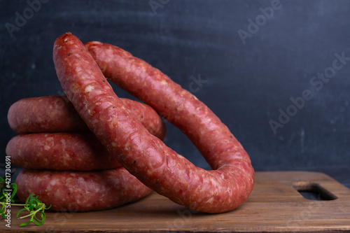 Rings of homemade Krakow sausage on a cutting board, copy-space