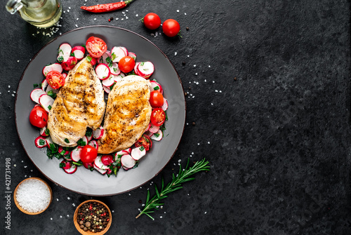 Grilled chicken breast and salad with fresh vegetables, tomatoes and radishes. Chicken meat with salad. Healthy food on stone background with copy space for your text