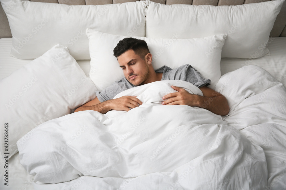 Handsome man sleeping under soft blanket in bed at home, above view Handsome man sleeping under soft blanket in bed at home, above view