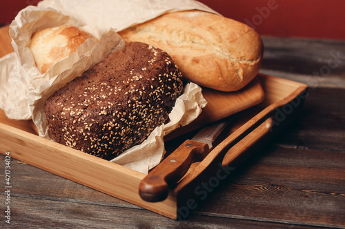 flour products rye bread on a tray and a sharp knife on the table