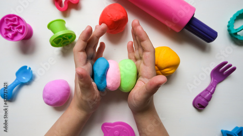 Foto Children's hands play with plastic multi-colored mass