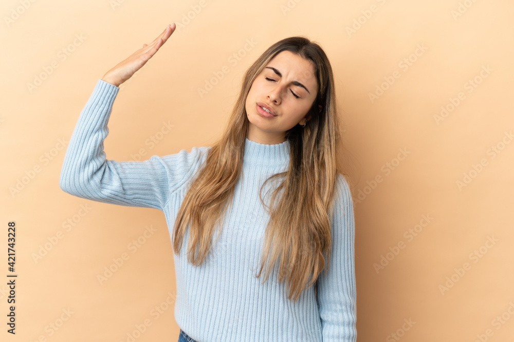 Fototapeta premium Young caucasian woman isolated on beige background with tired and sick expression