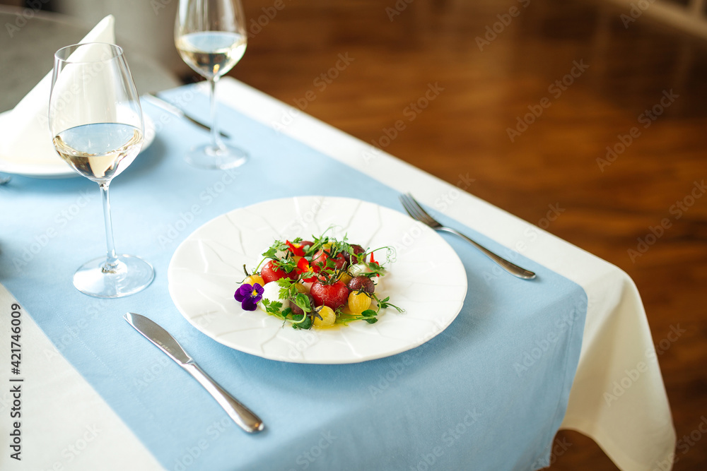 Gourmet peeled tomatoes salad on the table with a glass of white wine Gourmet peeled tomatoes salad on the table with a glass of white wine