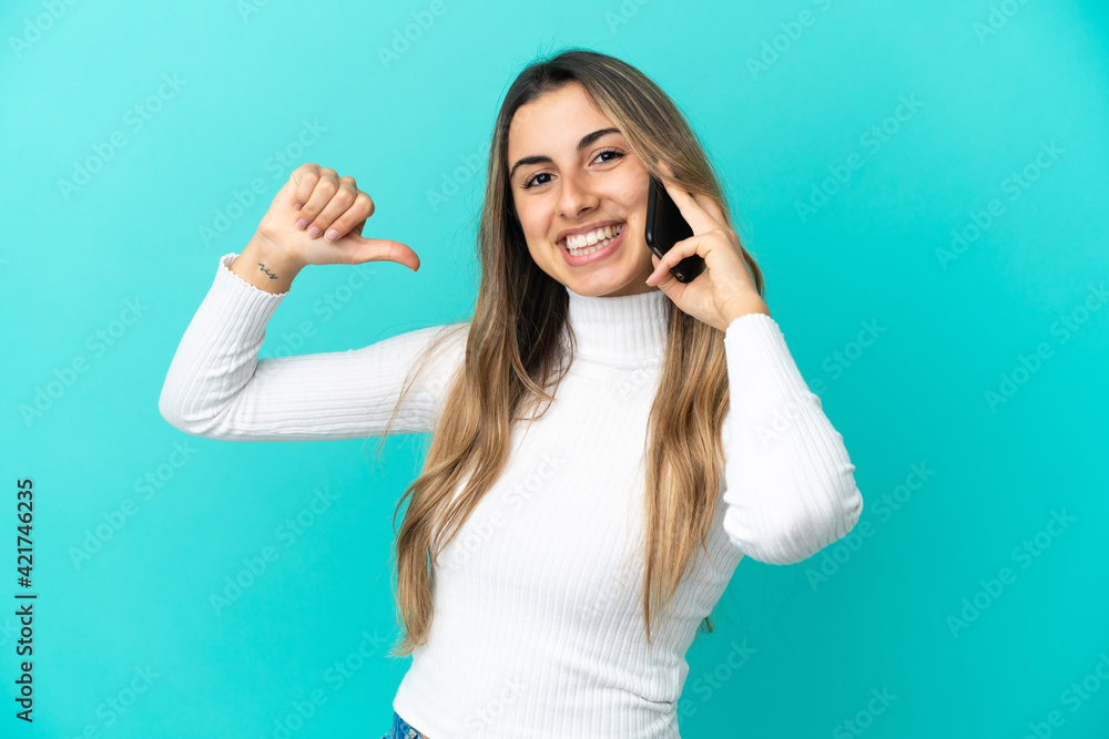 Fototapeta premium Young caucasian woman using mobile phone isolated on blue background proud and self-satisfied