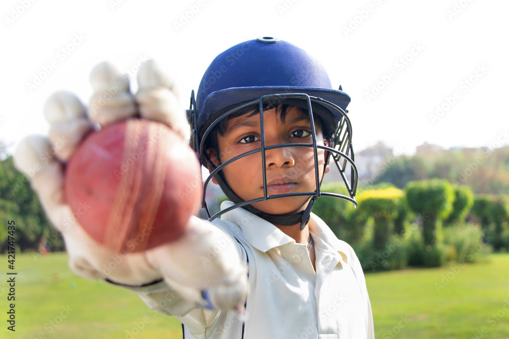 Portrait of boy wearing cricket helmet and Showing cricket ball Stock