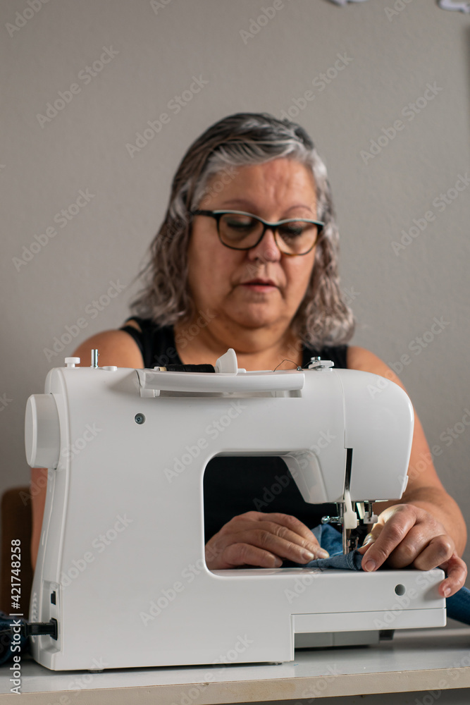 Front shot of a lady sewing with a sewing machine.