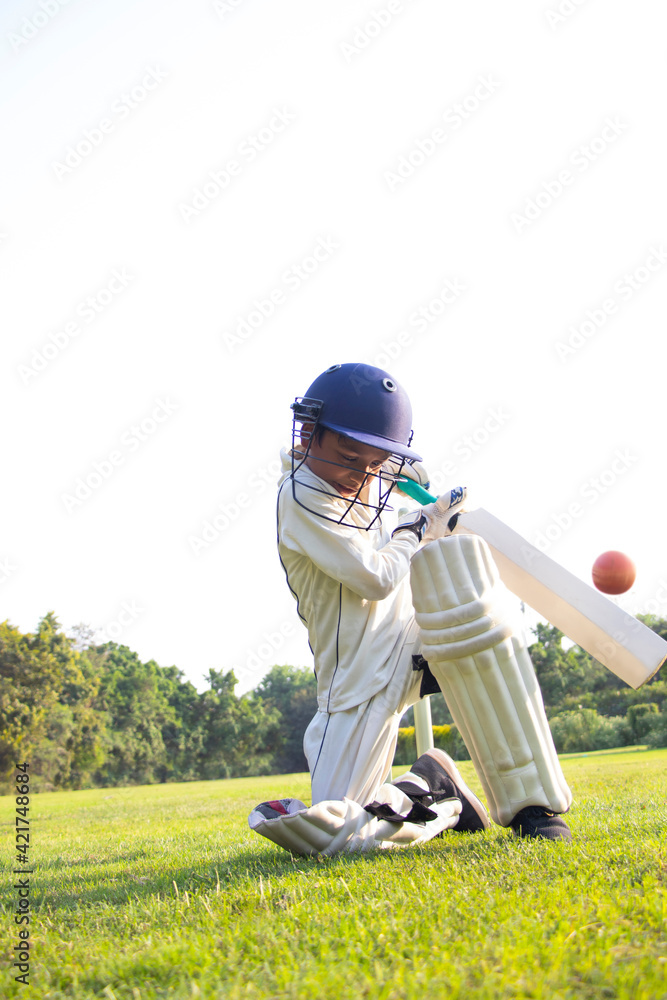 Young boy batting in protective gear during a cricket Young boy batting in protective gear during a cricket