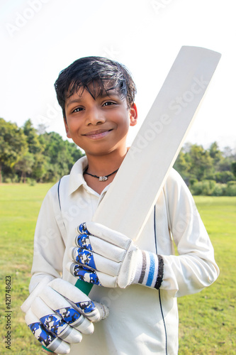 Photography Boy in cricket uniform holding a cricket bat