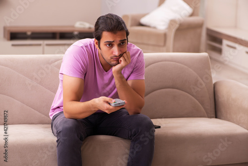 Young man watching tv at home during pandemic