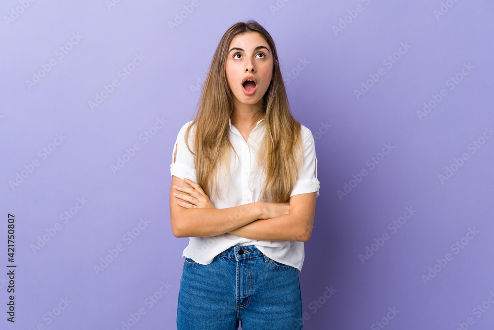 Young woman over isolated purple background looking up and with surprised expression Young woman over isolated purple background looking up and with surprised expression