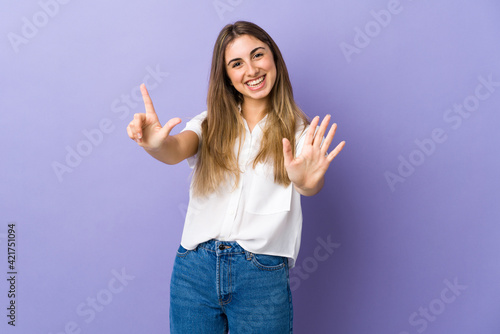 Young woman over isolated purple background counting seven with fingers