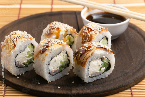 sushi, rolls on a plate with chopsticks, on a wooden background 