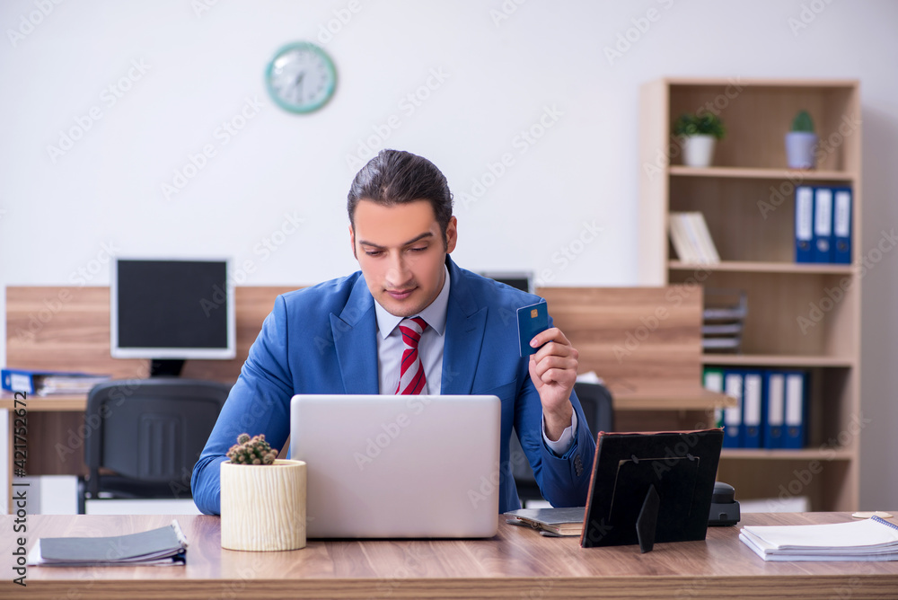 Young male employee holding credit card in the office Young male employee holding credit card in the office