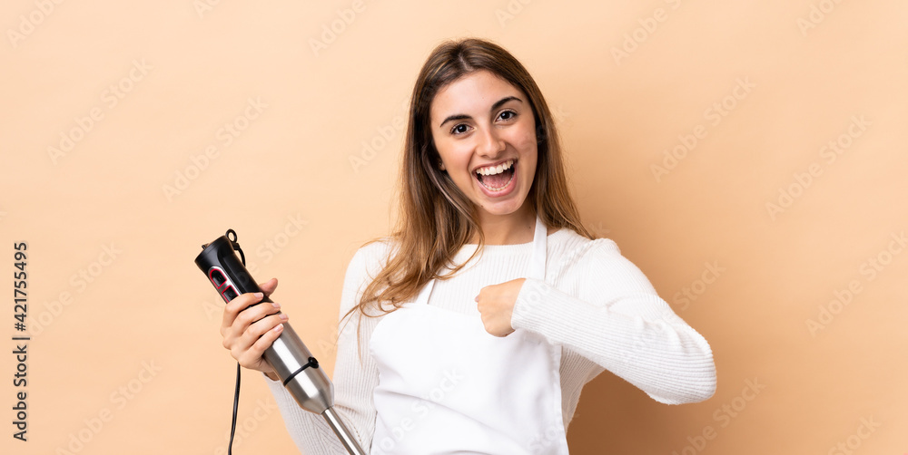 Woman using hand blender over isolated background with surprise facial expression Woman using hand blender over isolated background with surprise facial expression