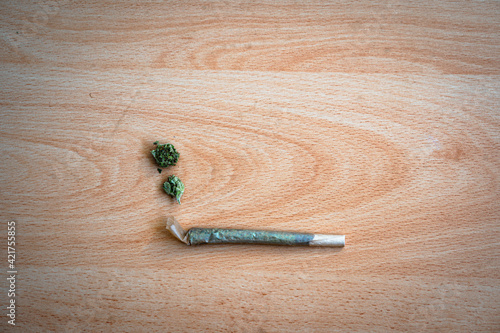 Rolled cannabis joint on a table with weed buds representing smoke photo