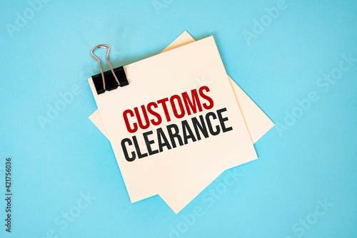 Text CUSTOMS CLEARANCE on sticky notes with copy space and paper clip isolated on red background.Finance and economics concept.