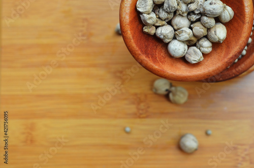 pepper, cardamom, and cinnamon in a wooden bowl on a wooden tray. close up with selective focus