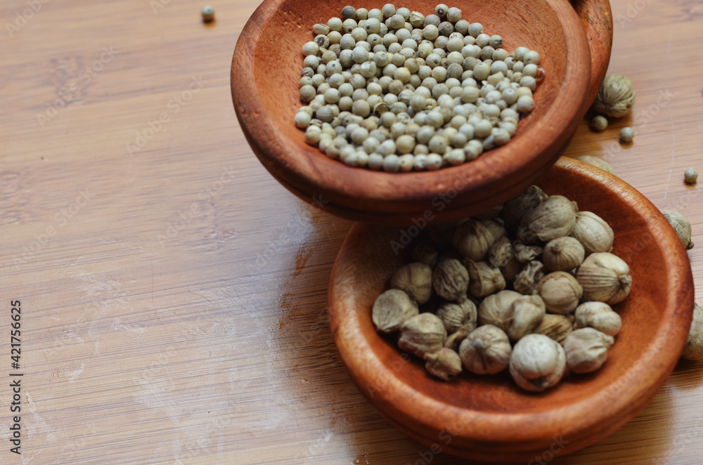 pepper, cardamom, and cinnamon in a wooden bowl on a wooden tray. close up with selective focus pepper, cardamom, and cinnamon in a wooden bowl on a wooden tray. close up with selective focus