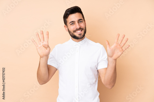 Caucasian handsome man isolated on beige background counting nine with fingers © luismolinero