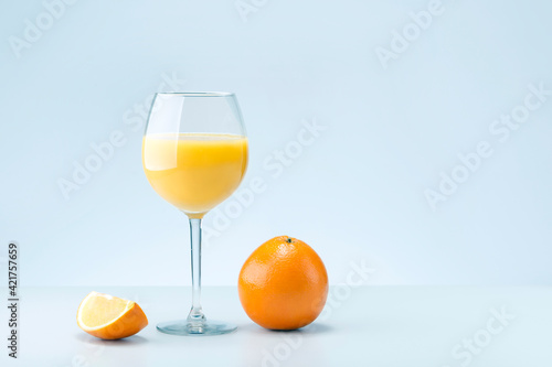 Glass of orange juice and oranges fruit on light grey background with place for text. Minimalism concept.