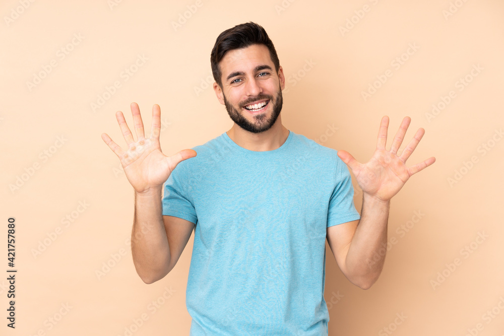 Fototapeta premium Caucasian handsome man isolated on beige background counting ten with fingers