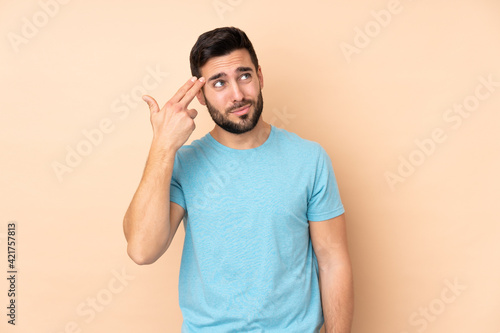 Caucasian handsome man isolated on beige background with problems making suicide gesture