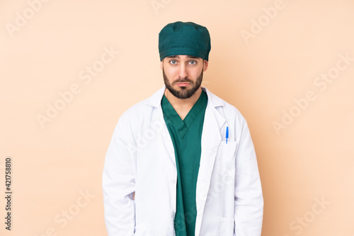 Surgeon man isolated on beige background sad