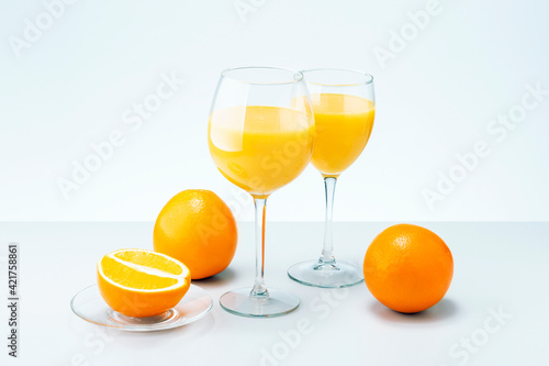 Orange fruit and two glasses of juice on grey surface. Healthy food and drink.