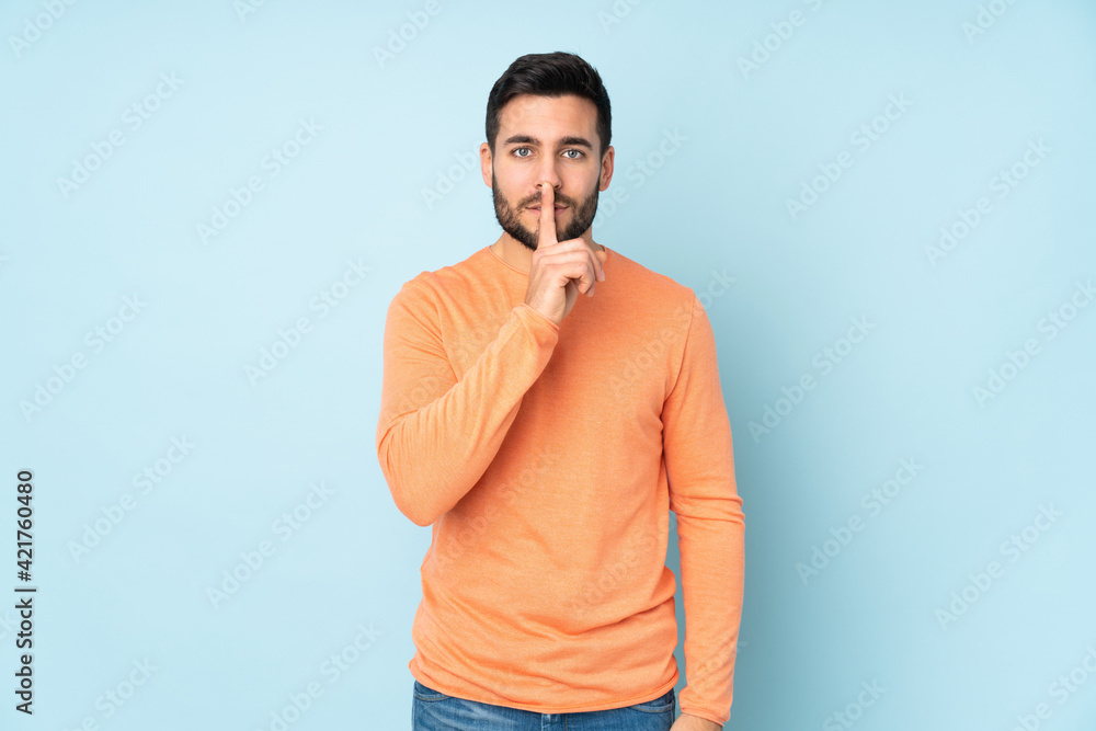 Caucasian handsome man showing a sign of silence gesture putting finger in mouth over isolated blue background Caucasian handsome man showing a sign of silence gesture putting finger in mouth over isolated blue background