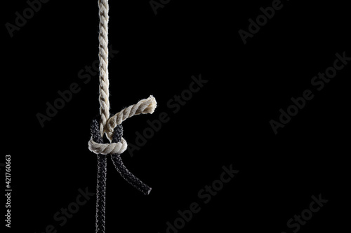 Black and white ropes are tied in a knot on a black background