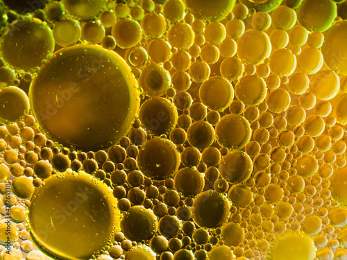 Colorful macro shot of olive oil bubbles in a colored glass of water