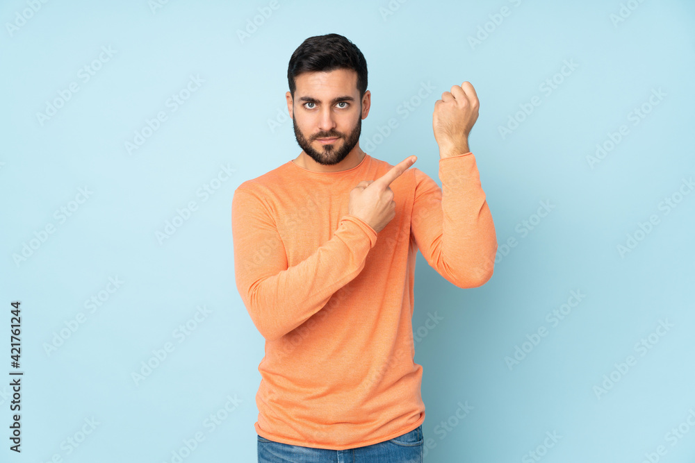 Fototapeta premium Caucasian handsome man making the gesture of being late over isolated blue background
