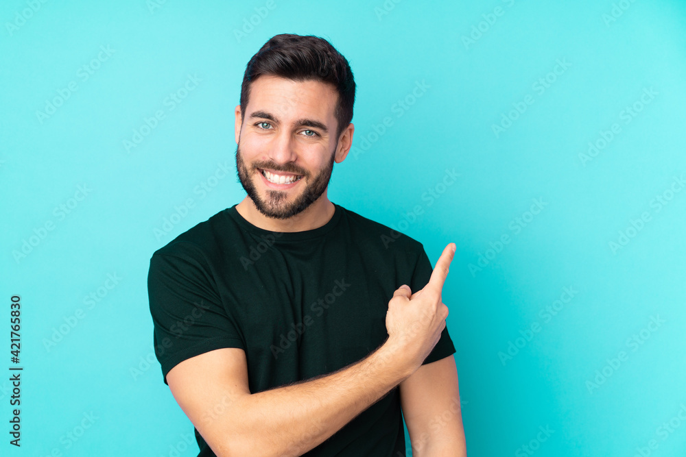 Caucasian handsome man isolated on blue background pointing to the side to present a product Caucasian handsome man isolated on blue background pointing to the side to present a product
