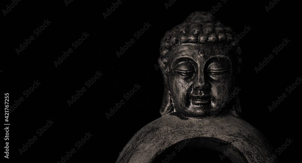 Close-up of a meditating Buddha statuette with closed eyes isolated on black background Close-up of a meditating Buddha statuette with closed eyes isolated on black background