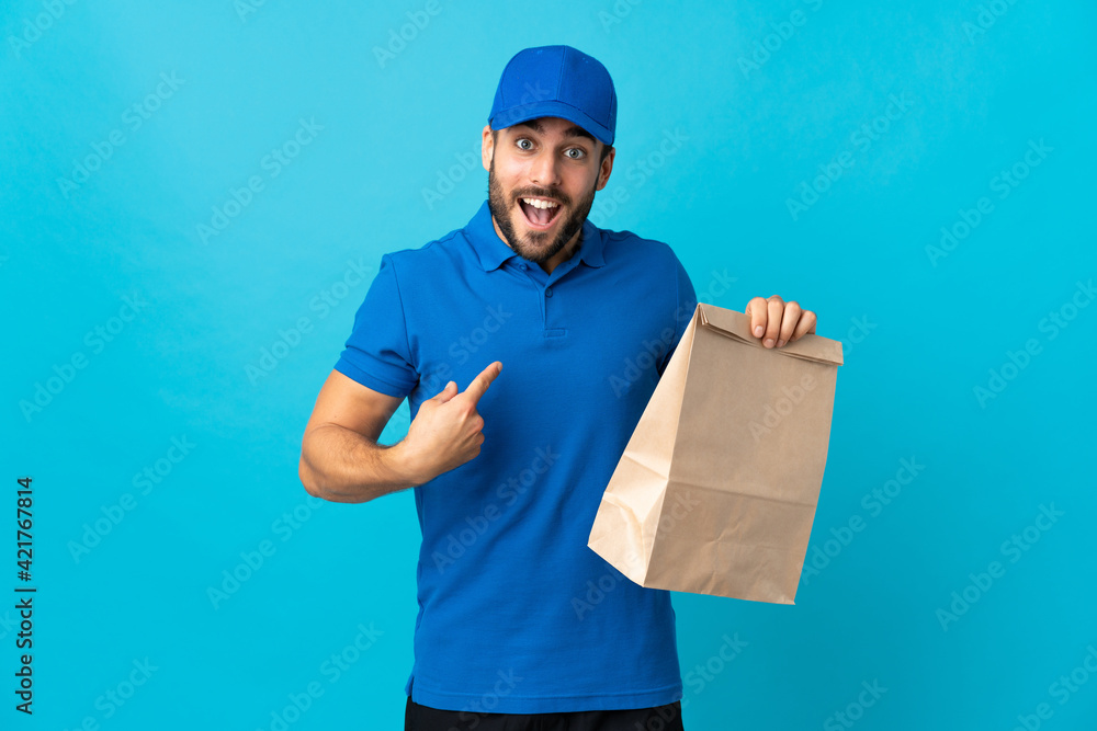 Delivery man with beard isolated on blue background with surprise facial expression Delivery man with beard isolated on blue background with surprise facial expression