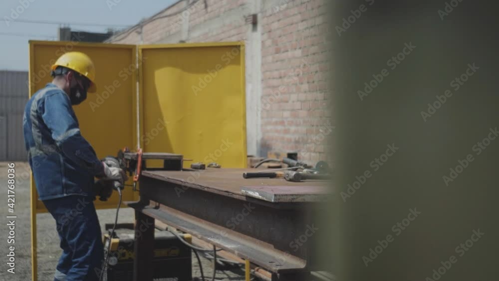 Plano entero hombre lijando fierro Plano entero hombre lijando fierro