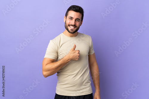 Young handsome man with beard over isolated background giving a thumbs up gesture